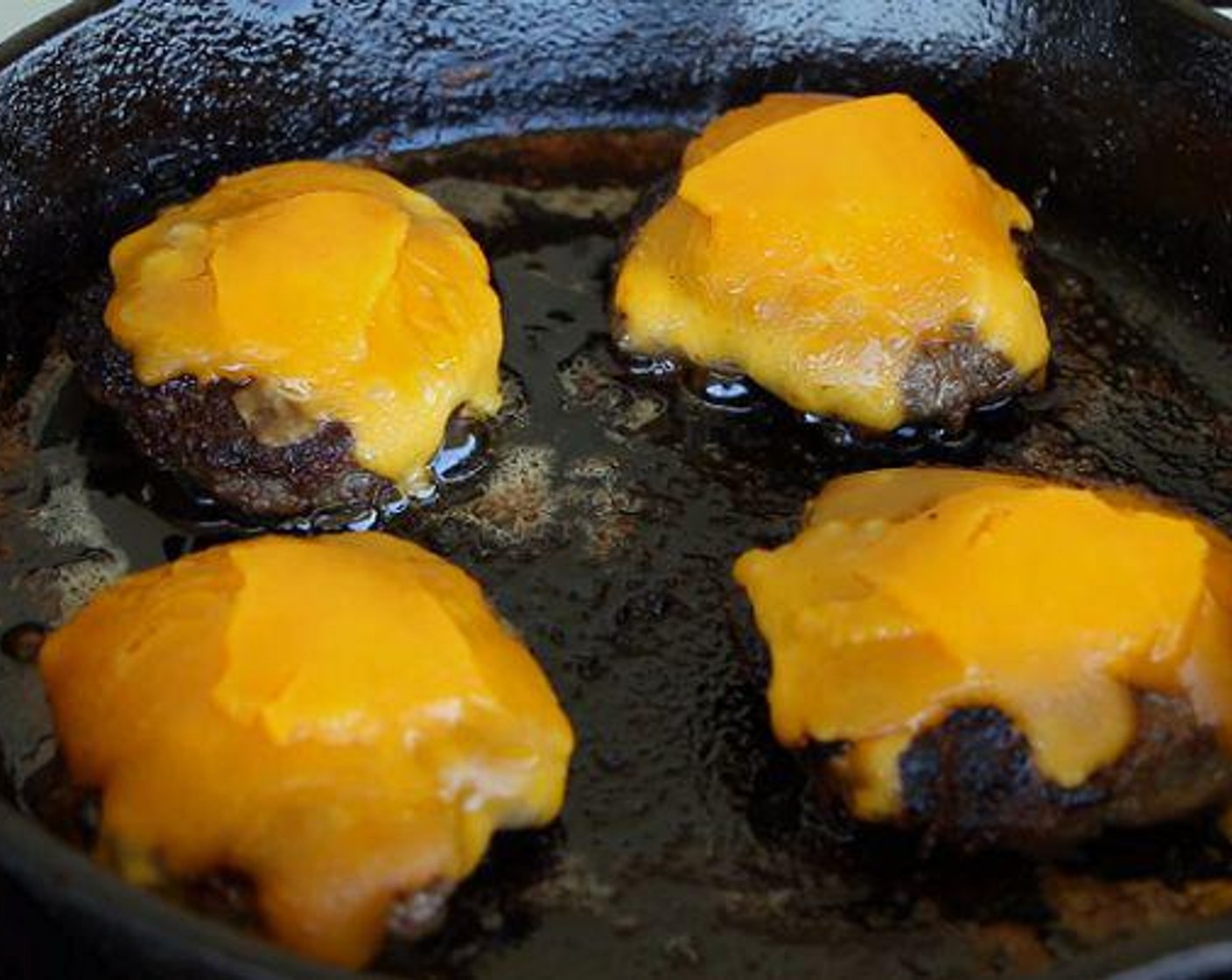 step 4 After about 5 minutes, flip each of the patties and add the Cheddar Cheese (4 slices). Cook for another 5-6 minutes or until the cheese is melted.