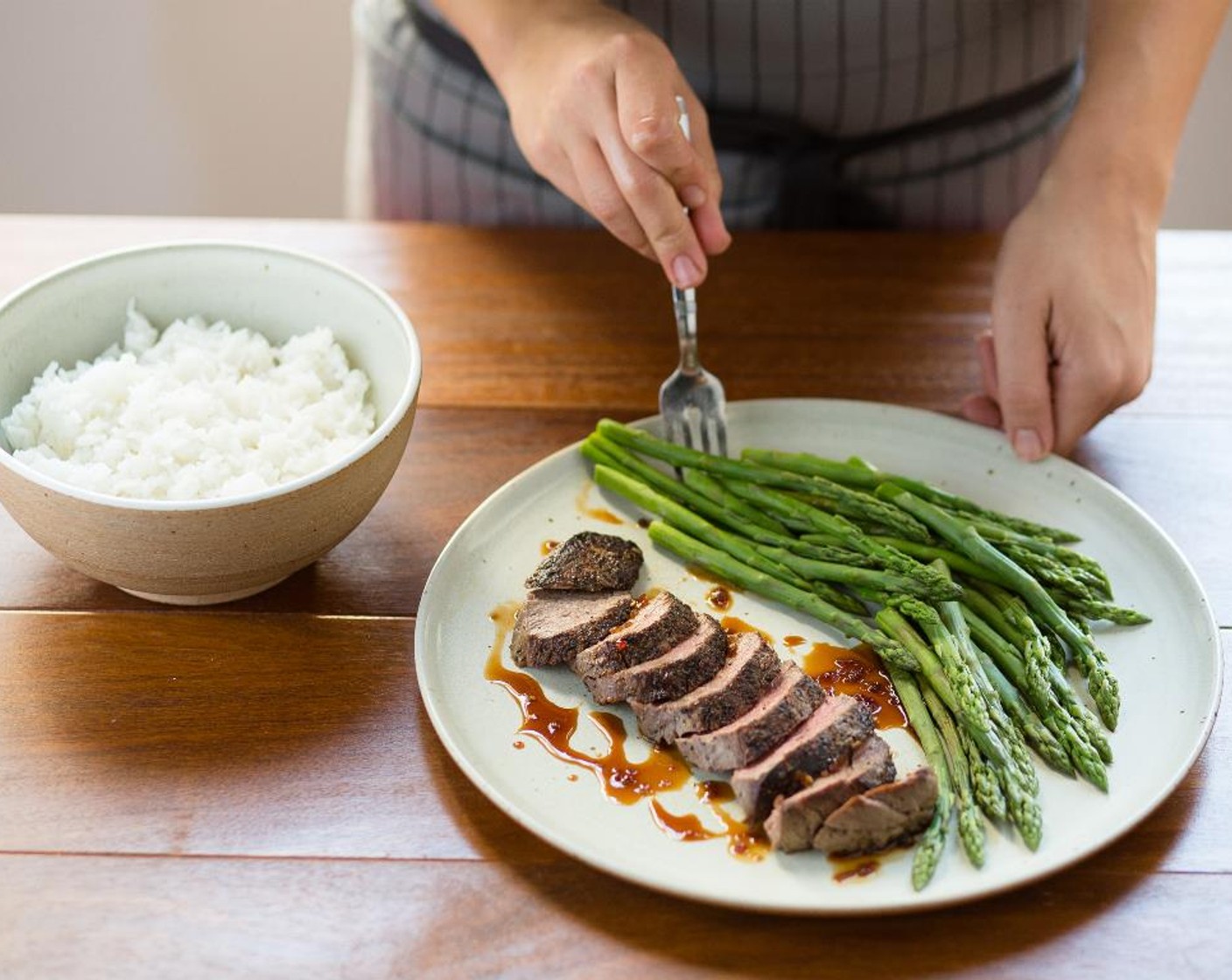 step 12 Place the asparagus in the center of two plates. Place the beef tenderloin next to the asparagus and spoon the Teriyaki reduction around the steak. Serve the jasmine rice on the side. Serve and enjoy!