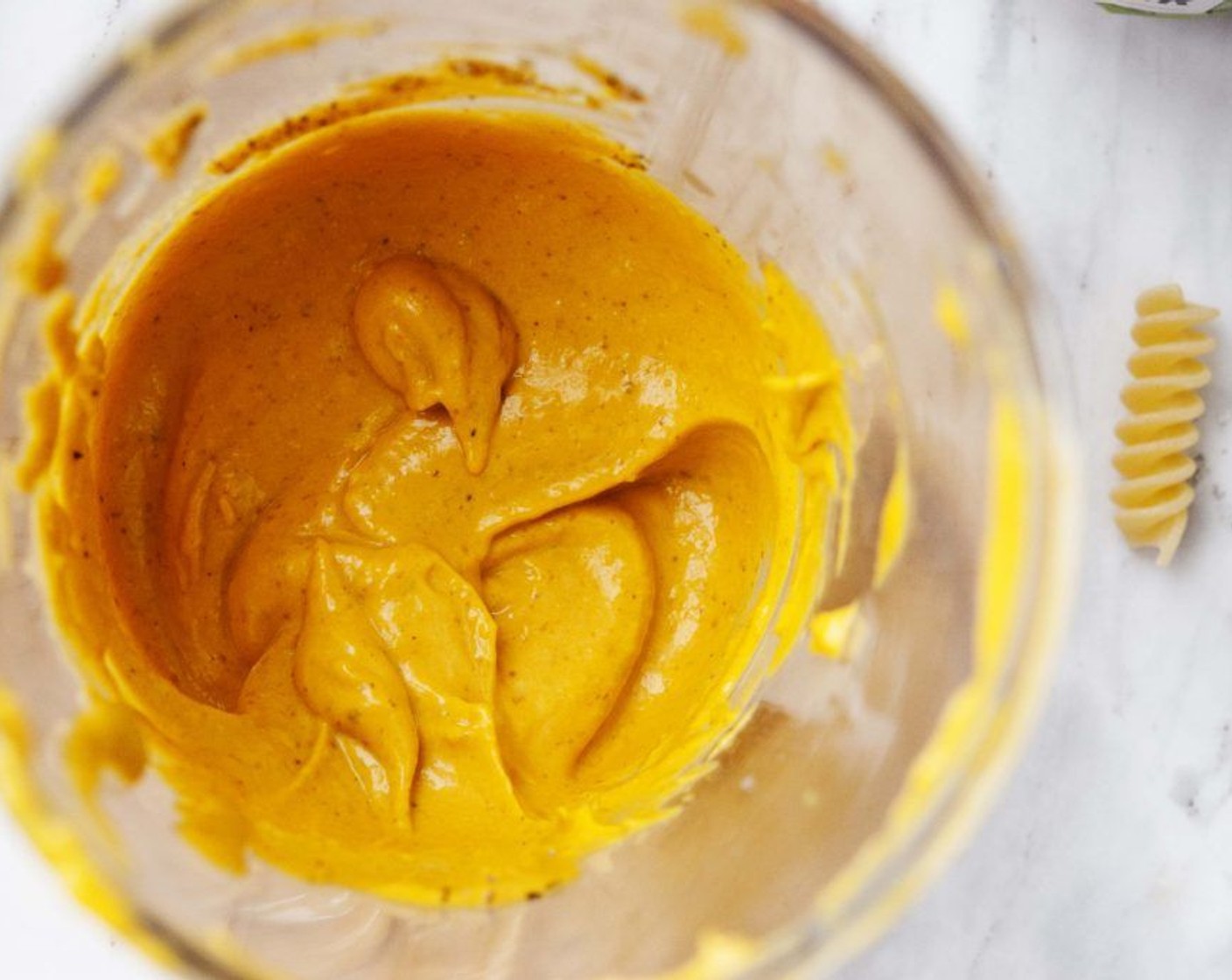 step 2 While the pasta is cooking, make the sauce. Place Butternut Squash (1/2 cup), Creamy Almond Butter (4 Tbsp), Tahini (2 Tbsp), Extra-Virgin Olive Oil (1 Tbsp), Nutritional Yeast (1 Tbsp), Coconut Vinegar (1 Tbsp), Salt (to taste) and Ground Black Pepper (to taste) into a bowl, and using an immersion blender puree them all until creamy. Add just as much Almond Milk (to taste) as needed to get the right consistency.