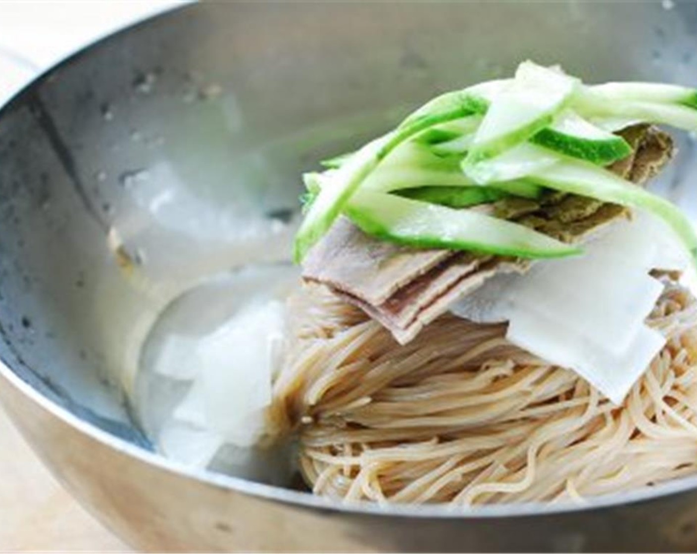 step 12 Place one serving of noodles in the middle of the serving bowl and top with the pickled radish, slices of beef, cucumber, and pear if using, and the Egg (1).