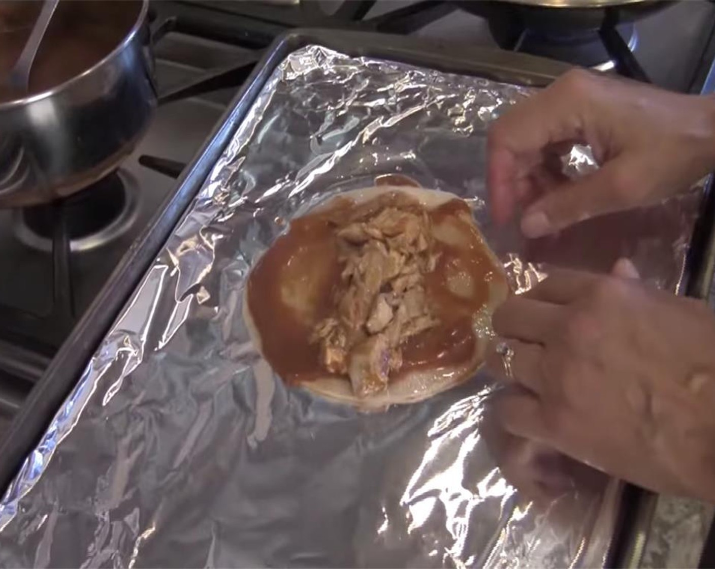 step 10 Spread a thin layer of sauce over each tortilla, and place spoonful of chicken down the center. Roll, and place in an oven proof dish. Cover with sauce, cheddar cheese, and some of the chopped onion.