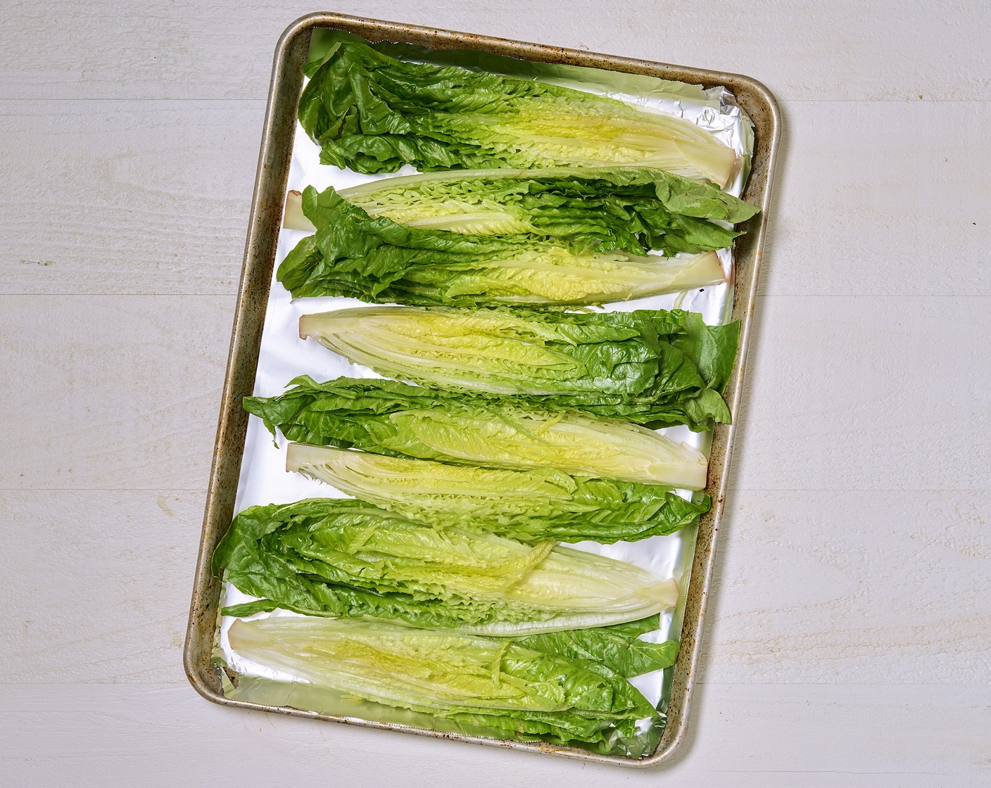 step 3 Drizzle Romaine Lettuce (2 heads) with Olive Oil (as needed) and place on a foil-lined baking sheet.