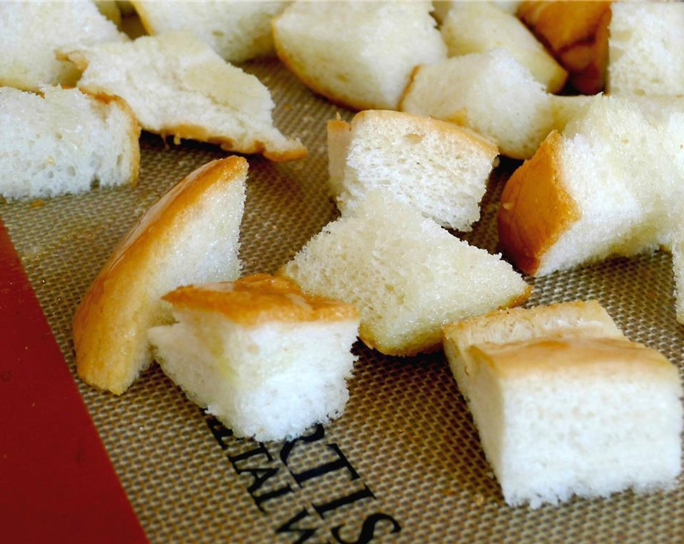 step 6 Toss the cubes of bread with the Olive Oil (2 Tbsp) and spread onto a baking sheet. Place in the oven for 8 minutes.