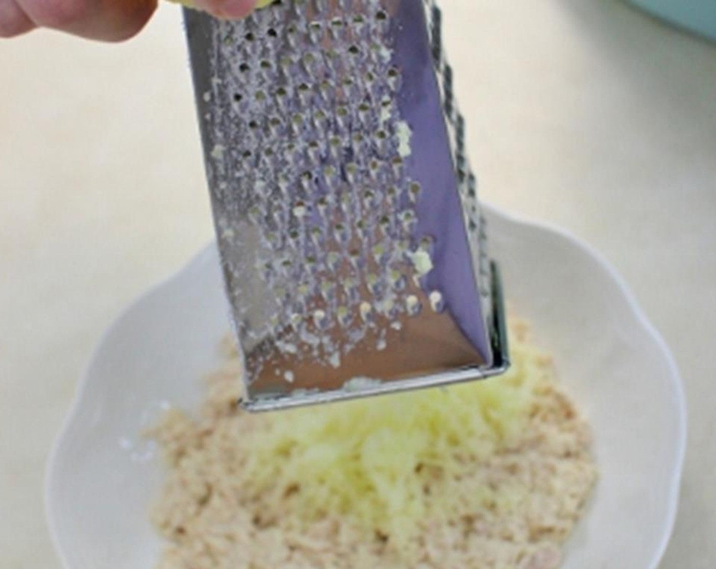 step 8 Using a box grater, finely grate about one and a half potatoes over the tuna on each salad.