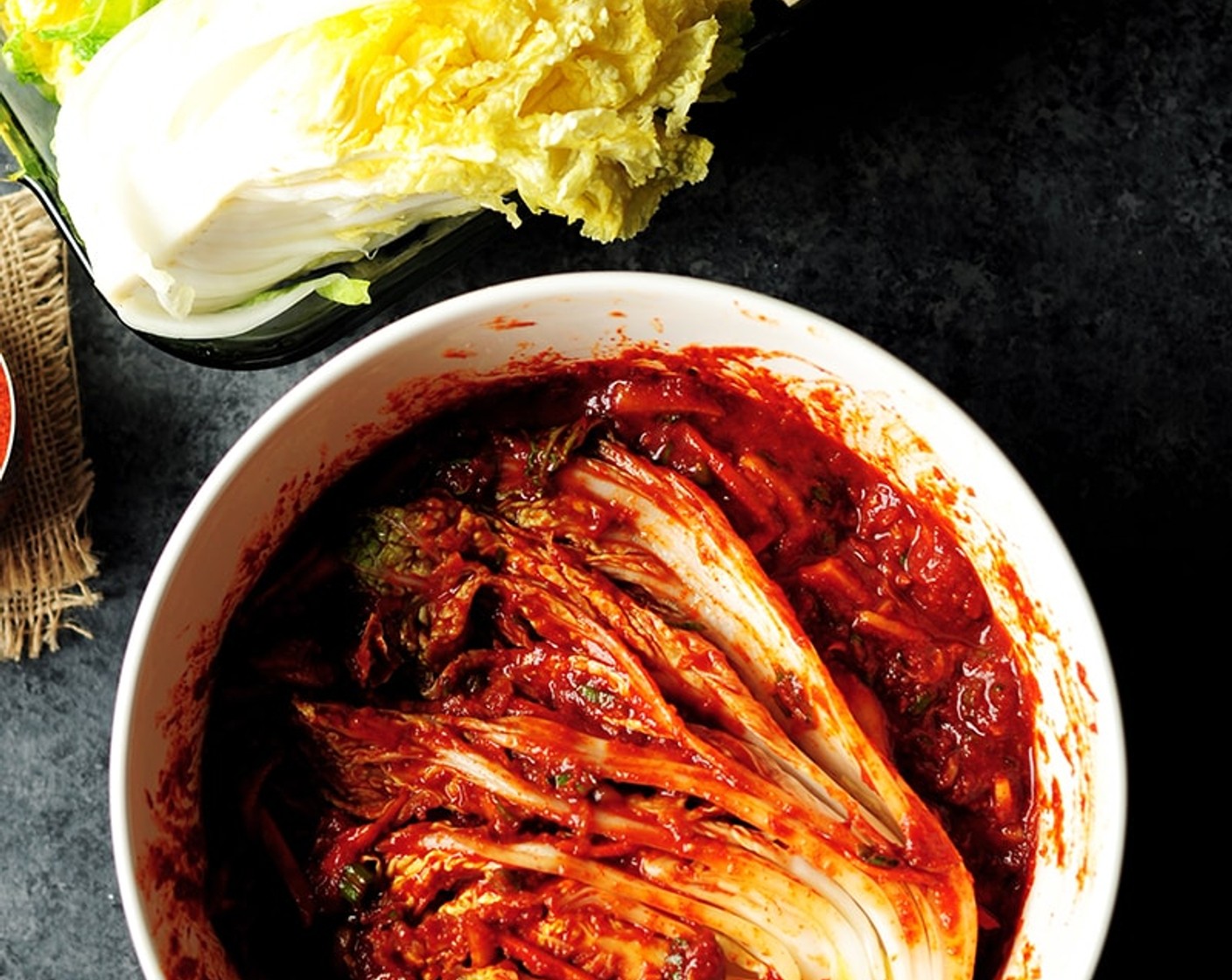 step 11 Time to make the kimchi. Wear gloves and press the cabbage quarters in the kimchi paste, one at a time, spreading some pastern each cabbage leaf. When the cabbage quarter is covered with the kimchi paste, lift it up and fold the leaves towards the core.