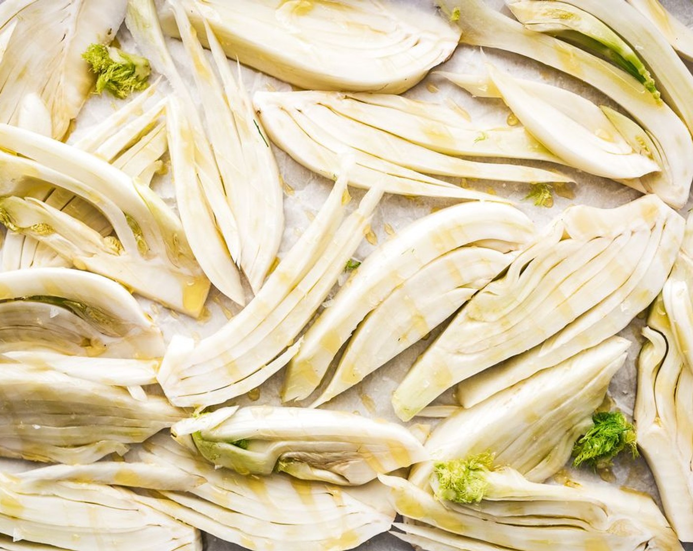 step 3 Arrange the thinly sliced Fennel Bulb (1) on the other parchment-lined sheet pan and drizzle with olive oil and season with a pinch of salt.