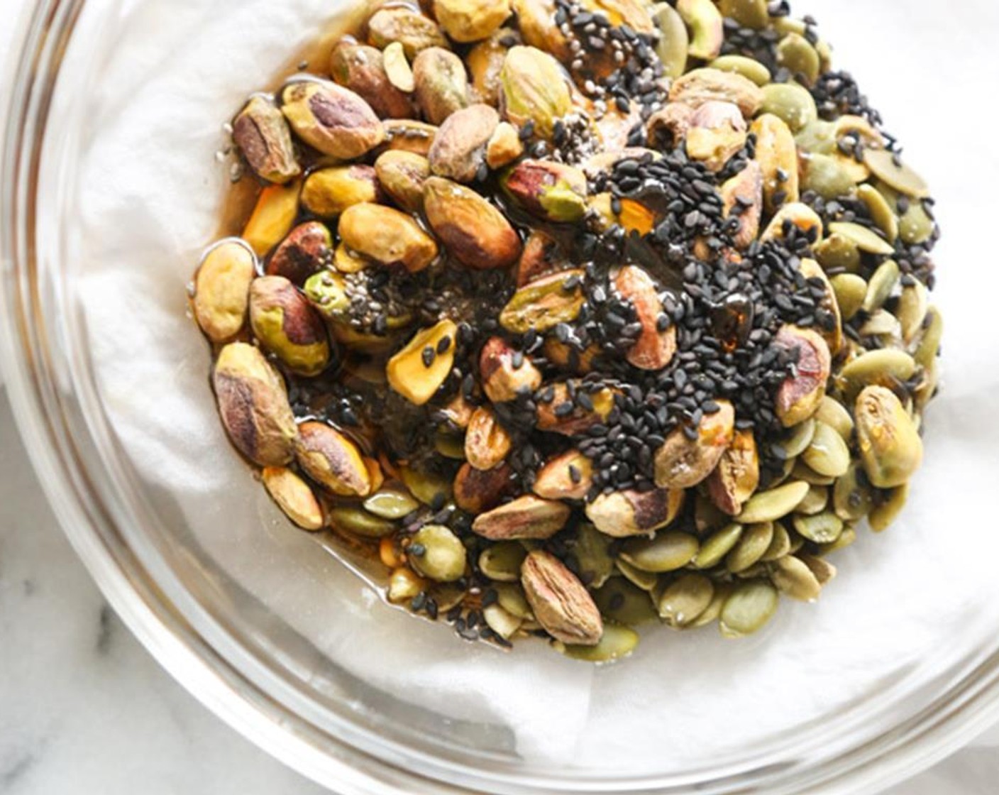 step 2 In a medium mixing bowl, combine the Pepitas (1/2 cup), Pistachios (1/2 cup), Chia Seeds (1 Tbsp), Black Sesame Seeds (1 Tbsp), Maple Syrup (2 Tbsp), Coconut Oil (1 tsp) and Sea Salt (1/4 tsp), and toss until evenly coated.