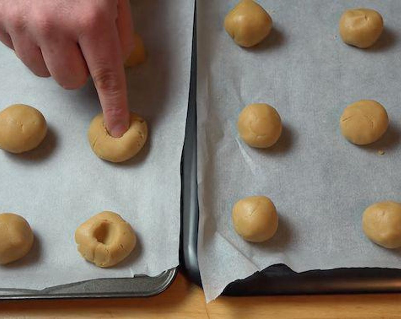 step 6 Using a clean thumb make a small indentation to each cookie ball. Spoon in a small amount of Raspberry Jam (1/3 cup) into each cookie dough hole.