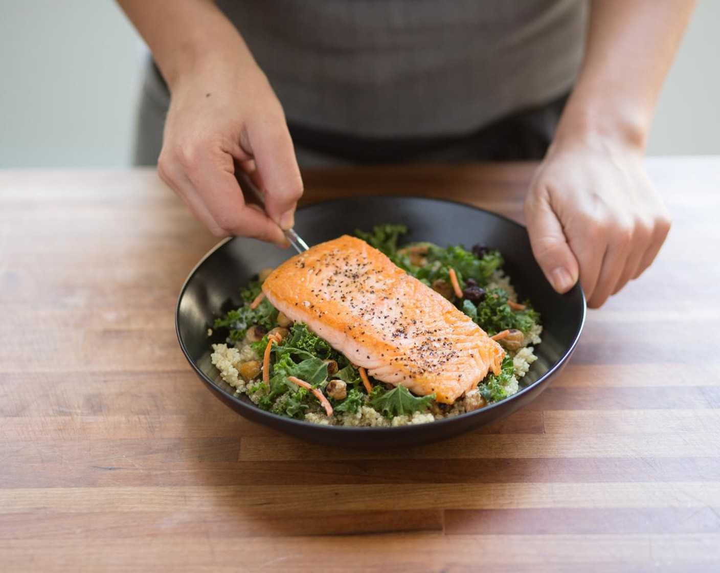 step 8 In the center of two bowls, place the quinoa. Add the kale salad, placing the seared salmon on top.
