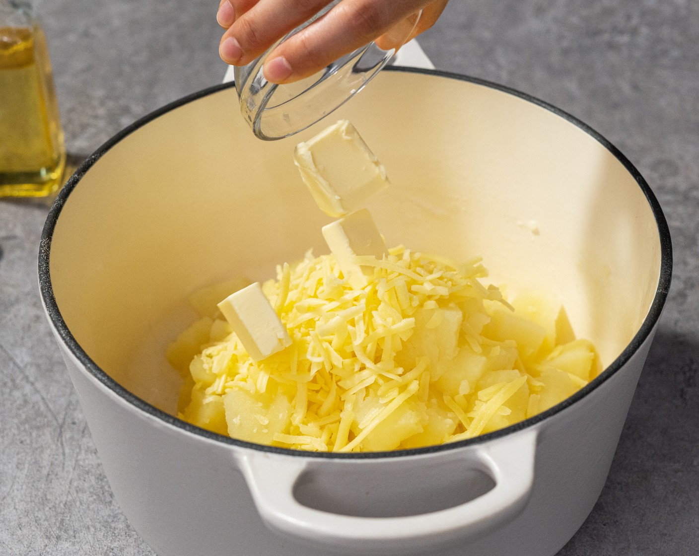 step 8 When the potatoes are cooked, drain and return them back to the warm pot. Add Cheddar Cheese (2/3 cup) and Butter (2 Tbsp), then use a masher to mash everything together.