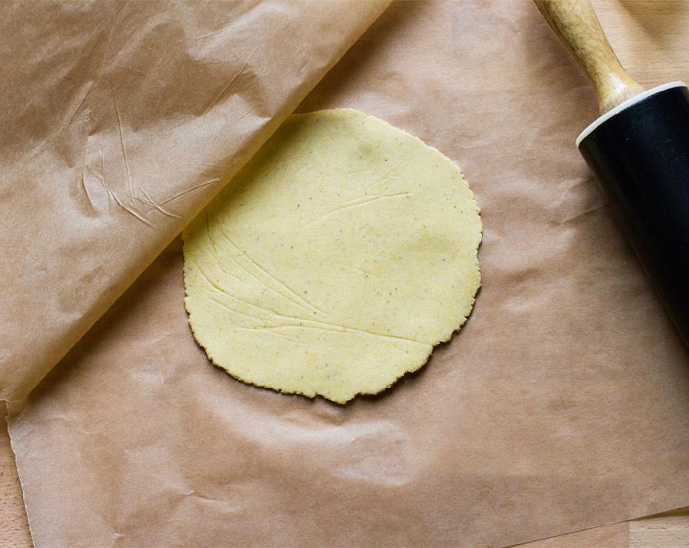 step 9 You want the dough to be about 6 inches in diameter and less than 1/8 inch thick. Use the rolling pin to continue flattening the dough. Keep the dough covered with parchment and roll lightly in varying directions to keep it in the circular shape.