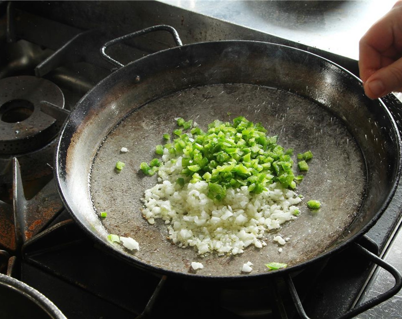 step 9 On a paella pan over medium high heat, add Olive Oil (3 Tbsp), diced green peppers, and onions. Season with Salt (to taste) to release the natural juices and cook until translucent.