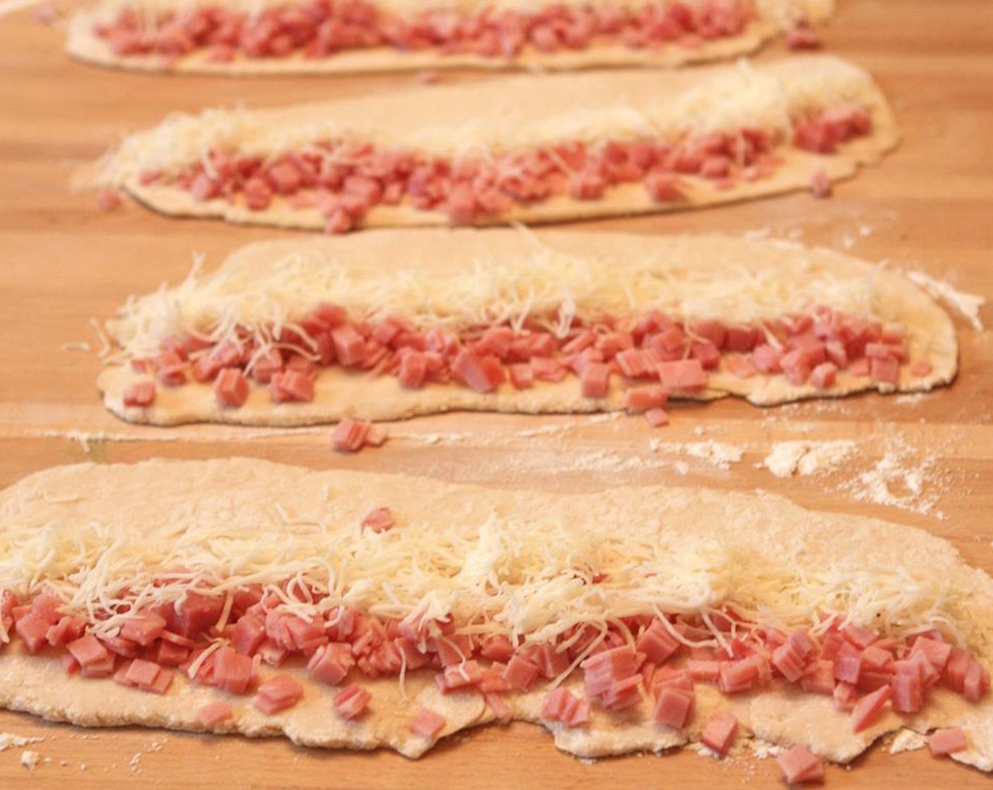 step 5 With the long side facing you, gently press 1/4 of the Ham (1/2 cup) and Mozzarella Cheese (1/2 cup) into the bottom third of the dough.