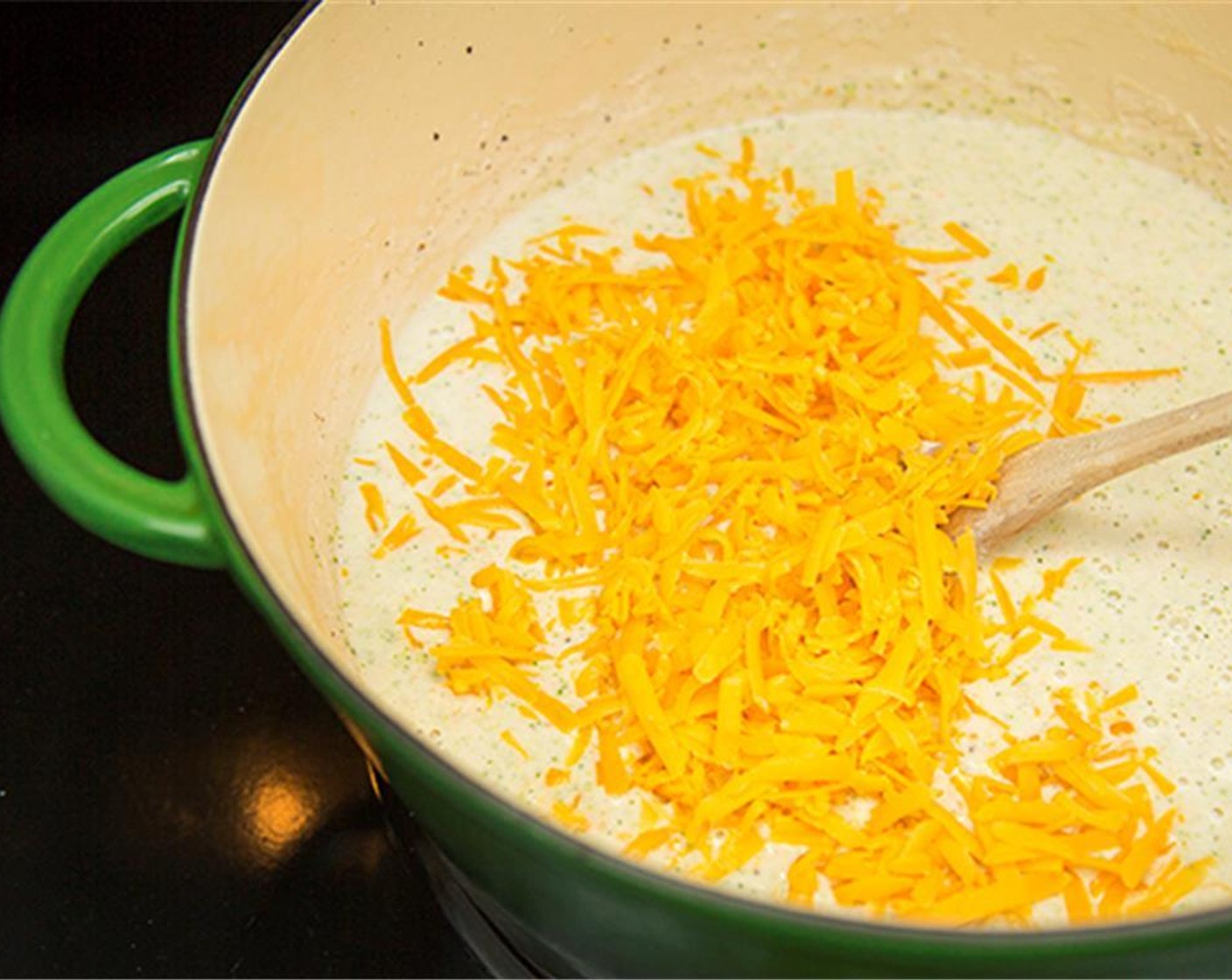 step 7 Add the White and Yellow Cheddar Cheese (2 1/2 cups) to the soup and whisk over medium heat until melted.