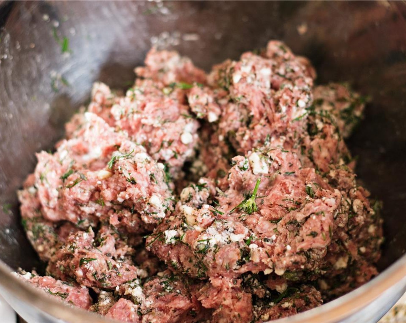 step 5 In a large bowl, use your hands to combine the Ground Lamb (2 lb), oregano, half of the chopped fresh dill, Coarse Sea Salt (1/2 Tbsp), and the crumbled feta.