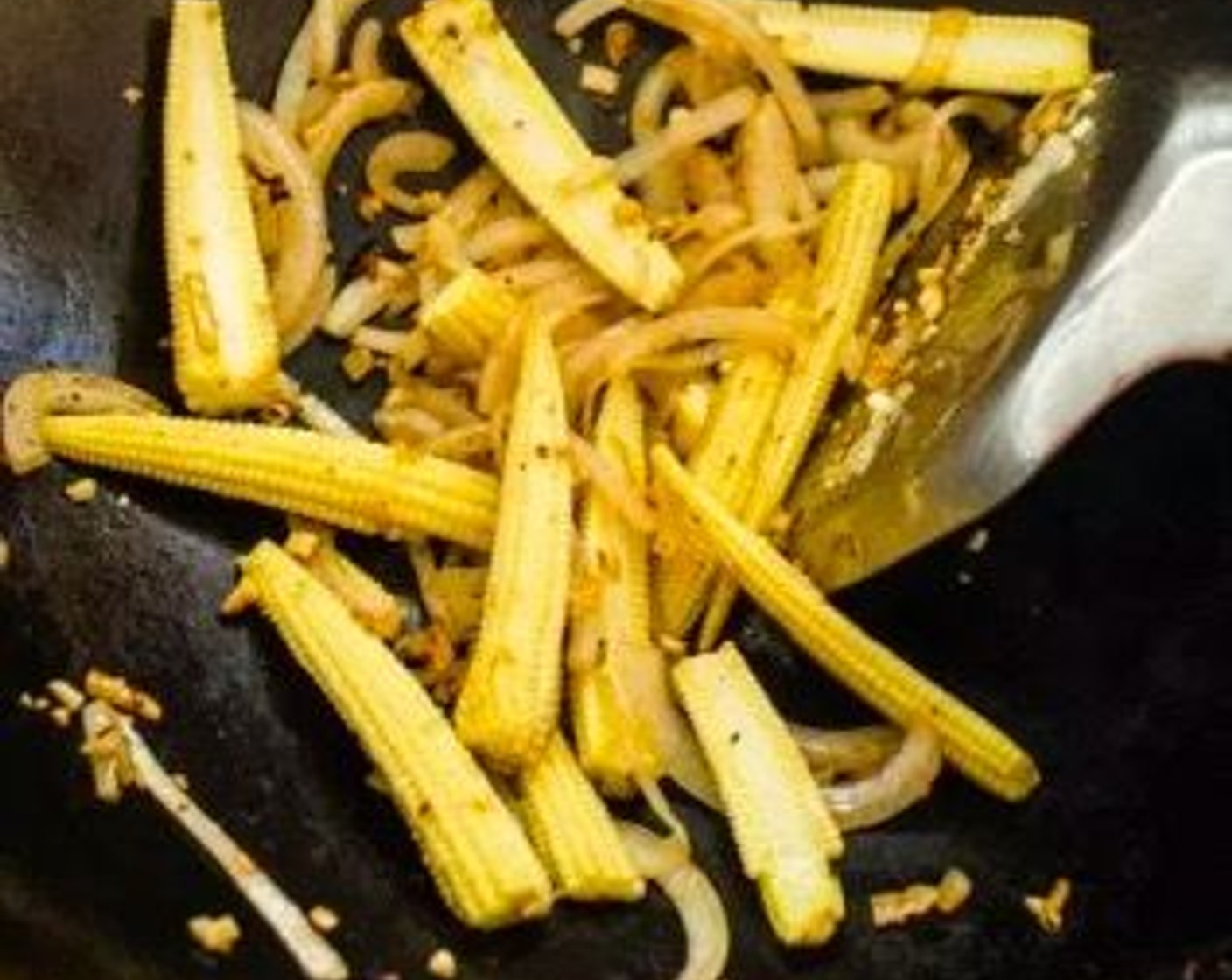 step 3 Add 1 tablespoon of Cooking Oil (1 Tbsp) to the wok, followed by the Garlic (2 cloves), Onion (1/2), and Baby Corn (6 pieces).