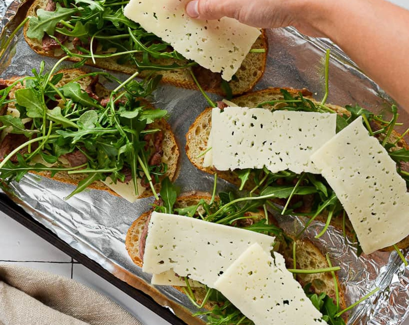 step 11 Place Arugula (2 cups) evenly on top of steak (around ½ cup each) and top with remaining slices of White Cheese (4 slices) per bread slice.