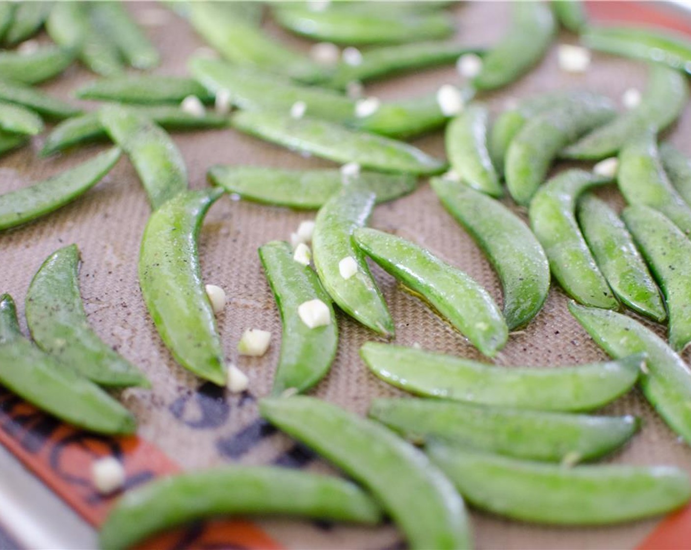 step 5 Lightly coat peas with olive oil. Spread on baking sheet, sprinkle with salt, pepper, and 1 minced garlic clove. Place in oven and bake for 8-10 minutes or until lightly browned. Adjust seasoning as necessary.