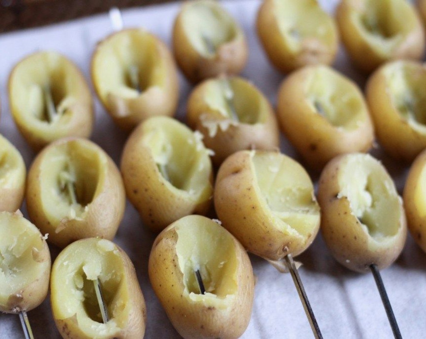 step 4 Use a paring knife to cut out an oval shape in the tops of the potatoes and gently scoop out the middles. Discard the waste or save it to throw into a potato salad. Skewer the potatoes and place them on the prepared baking sheet.