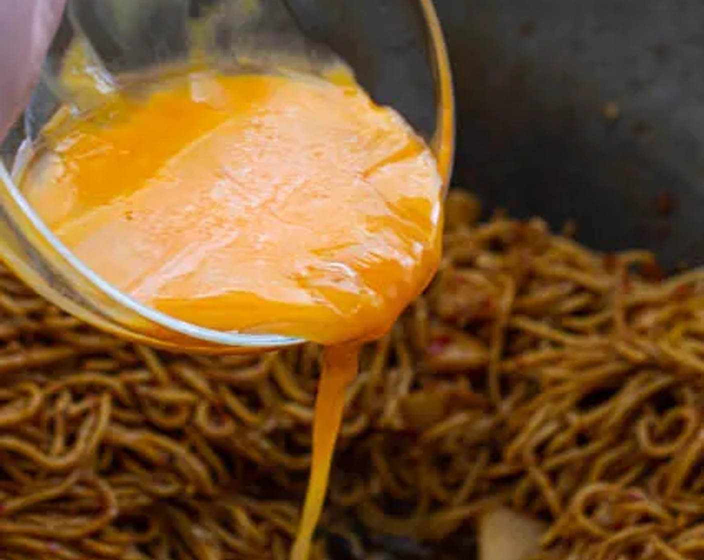 step 11 Separate the noodles to make a well in the middle of the wok, then pour Eggs (2) into the well. Stir-fry to distribute the eggs in the noodles evenly.