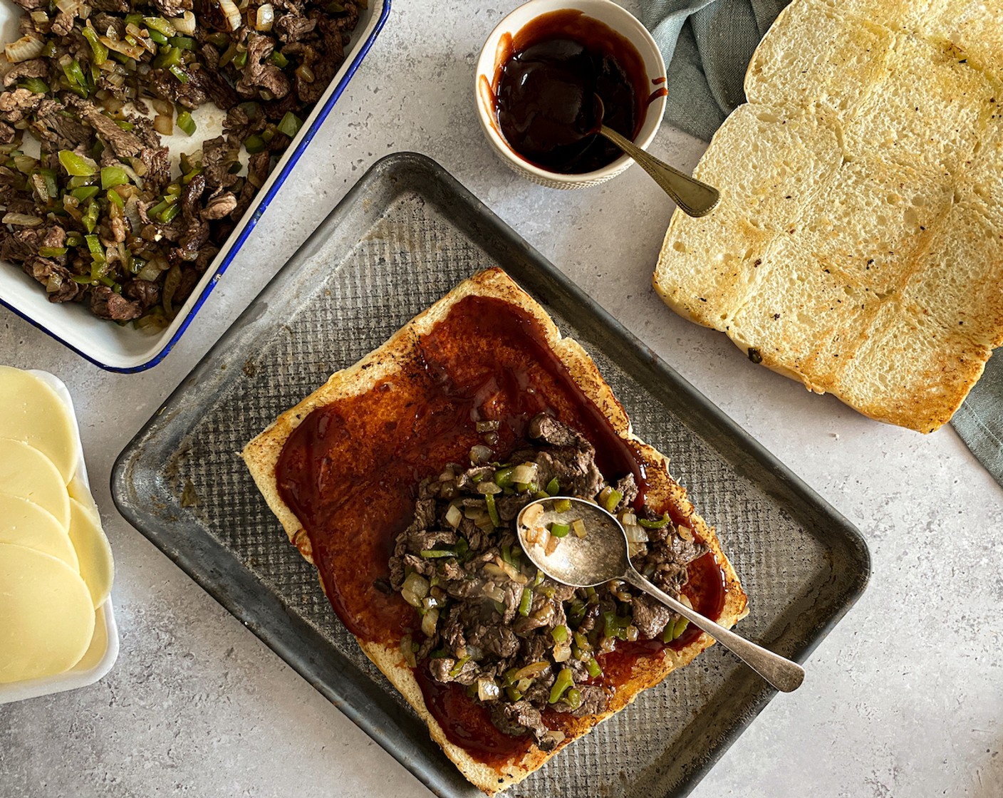 step 7 Spread toasted base with Smoky BBQ Sauce (1/2 cup). Feel free to spread sauce on the inside of the top piece too. Top generously with Philly beef mixture.