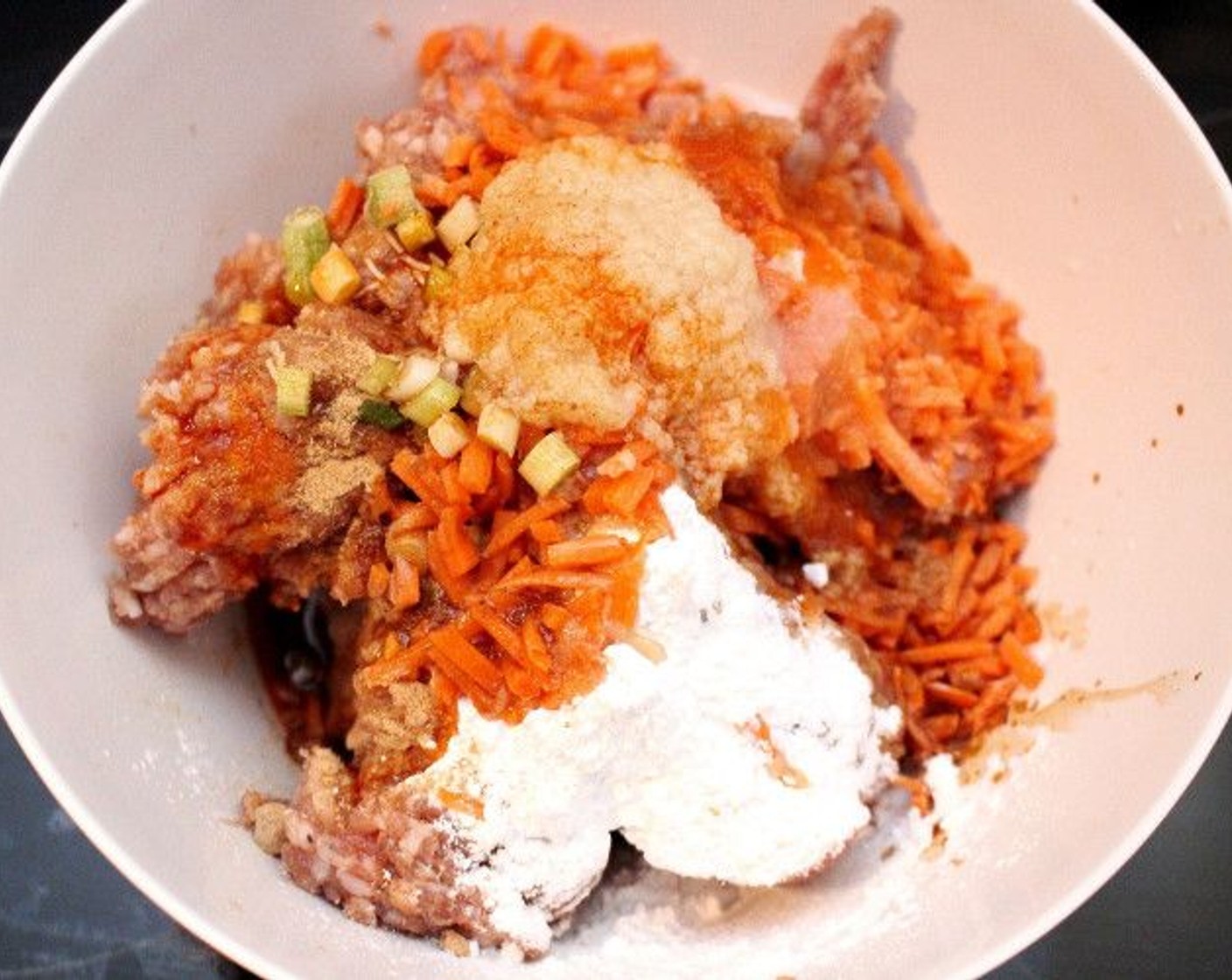 step 1 In a bowl add Ground Pork (1 lb), Carrot (1 cup), Scallions (2 Tbsp), Fresh Cilantro (2 Tbsp), Corn Starch (1 Tbsp), white part of Eggland's Best Classic Egg (1), Toasted Sesame Oil (1 Tbsp), Chili Oil (1 tsp), Granulated Garlic (1 pinch), Ground Ginger (1 pinch), and a bit of Soy Sauce (to taste).