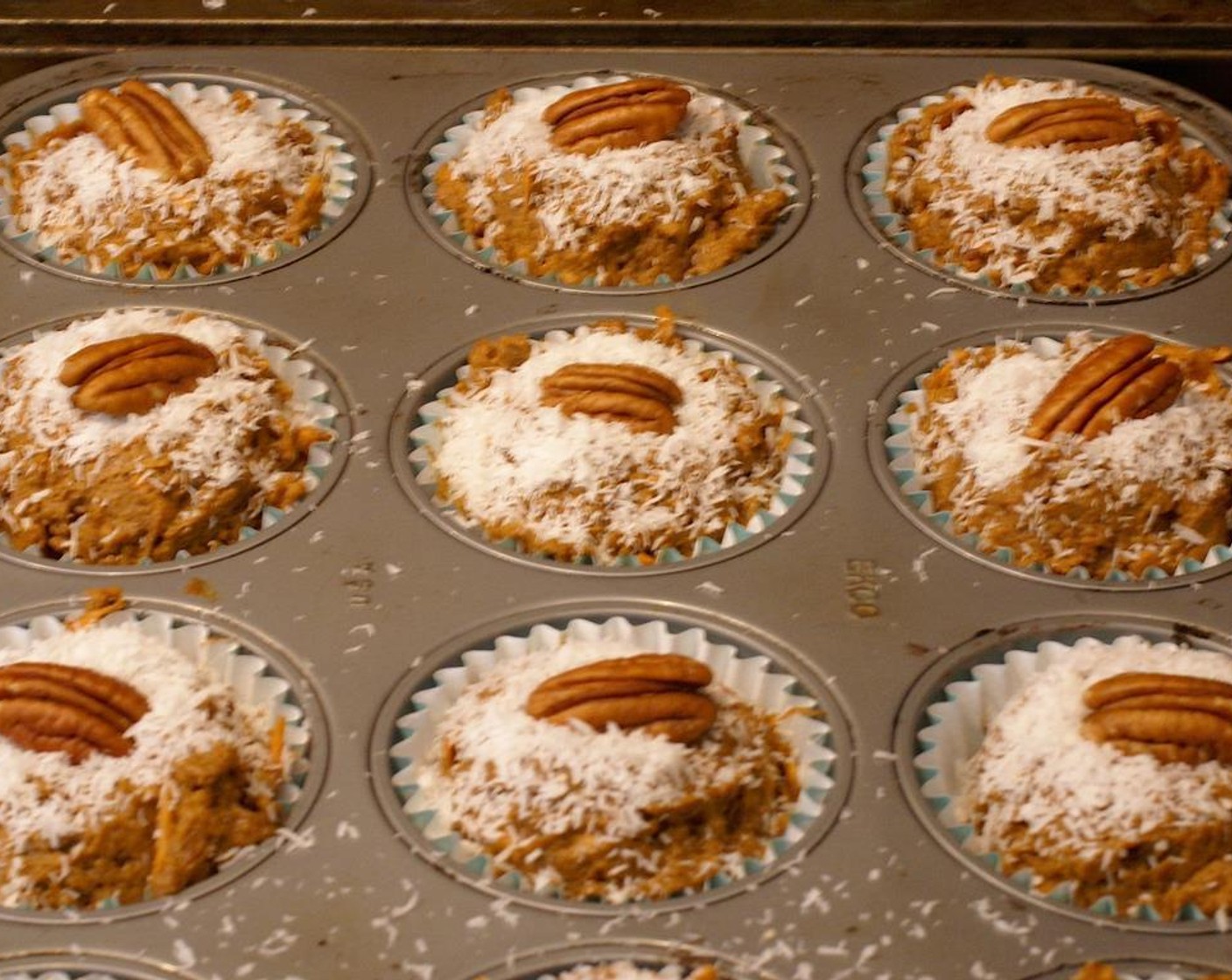 step 7 Scoop 1/4 cup of the batter into each muffin tin. Sprinkle with Unsweetened Shredded Coconut (to taste) and push a Pecan Halves (to taste) the center of each muffin.