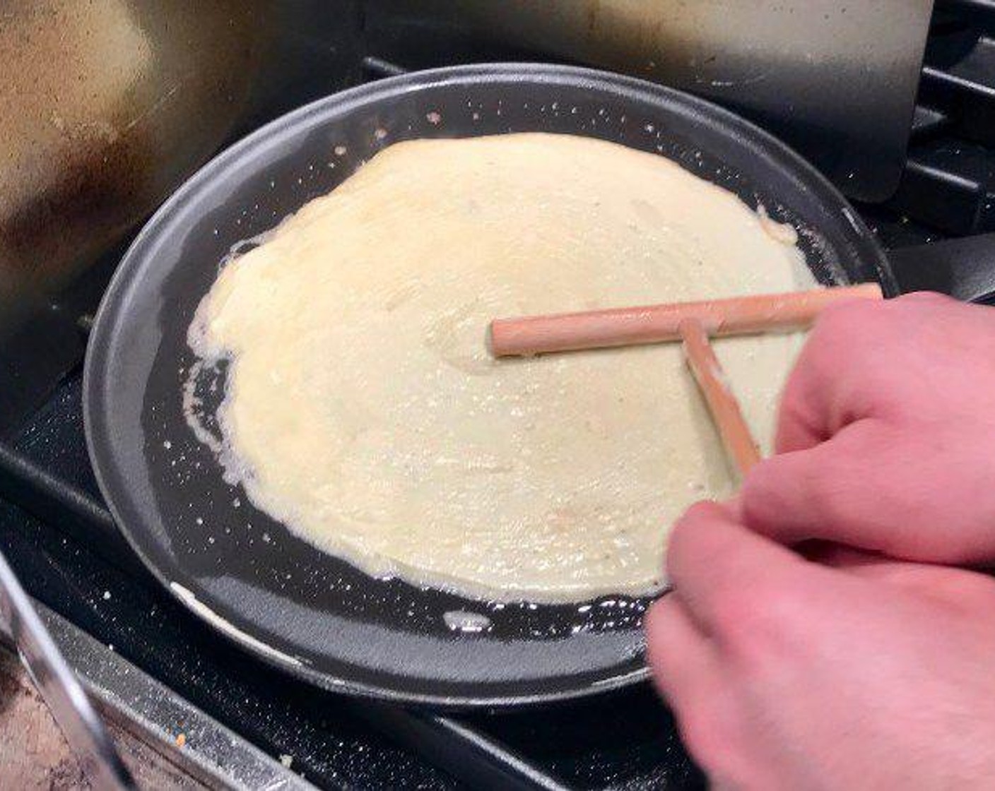 step 3 Grease your crêpe pan with butter over medium high heat. Pour 1/3 cup batter into the middle of the pan and then spread it into a large even circle with the crêpe paddle by spinning it 360 degrees.