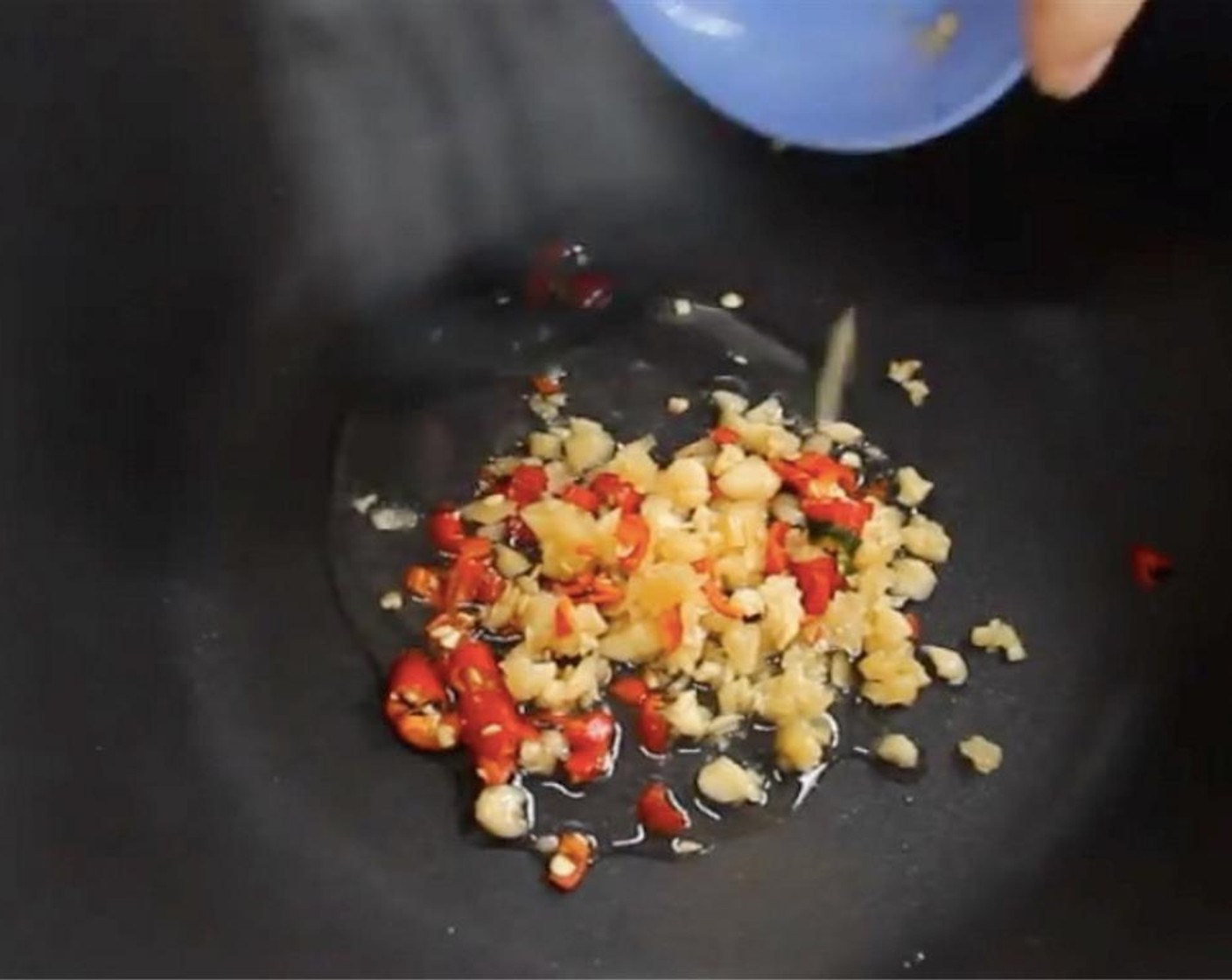 step 6 In a wok, add in oil on medium high heat. Sauté Garlic (2 cloves) and chili padi together until golden brown.