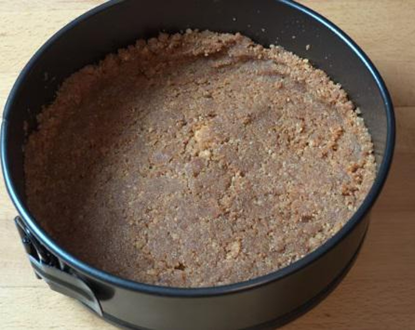 step 2 Grease the sides of a cake pan with some oil, and line the bottom with non stick baking paper. Transfer the cookie butter mixture to the pan, and using the bottom of a glass, press the mixture evenly to flatten it. Put the pan in the fridge while you work with the rest of the ingredients.