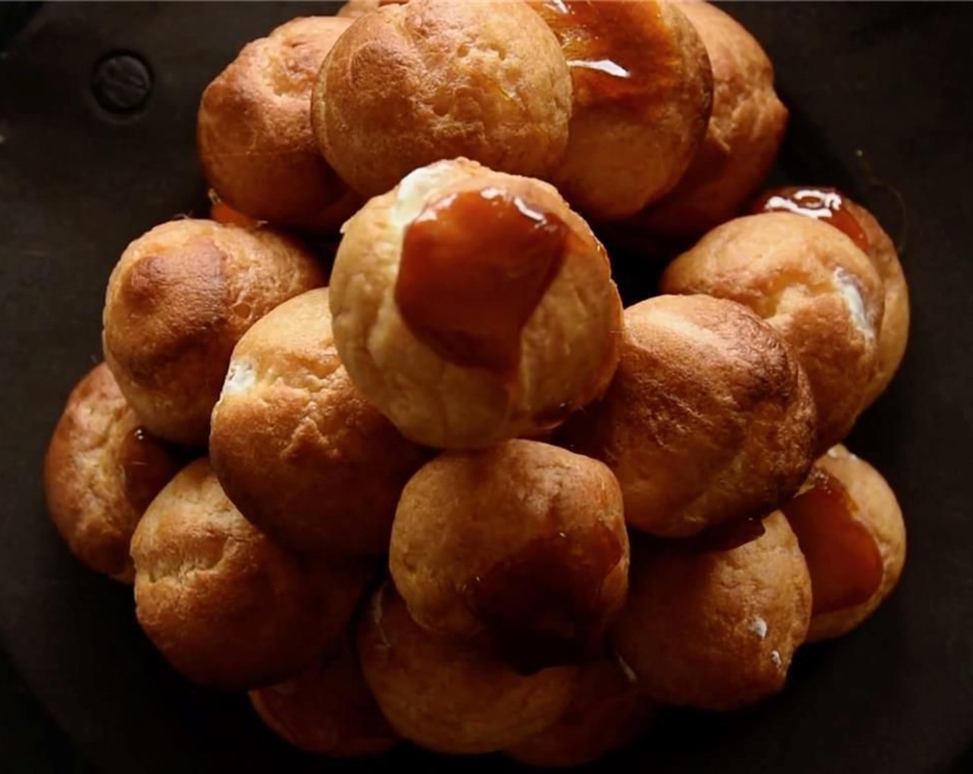 step 26 Carefully, dip each choux bun into the caramel and top with a shard of coconut praline.