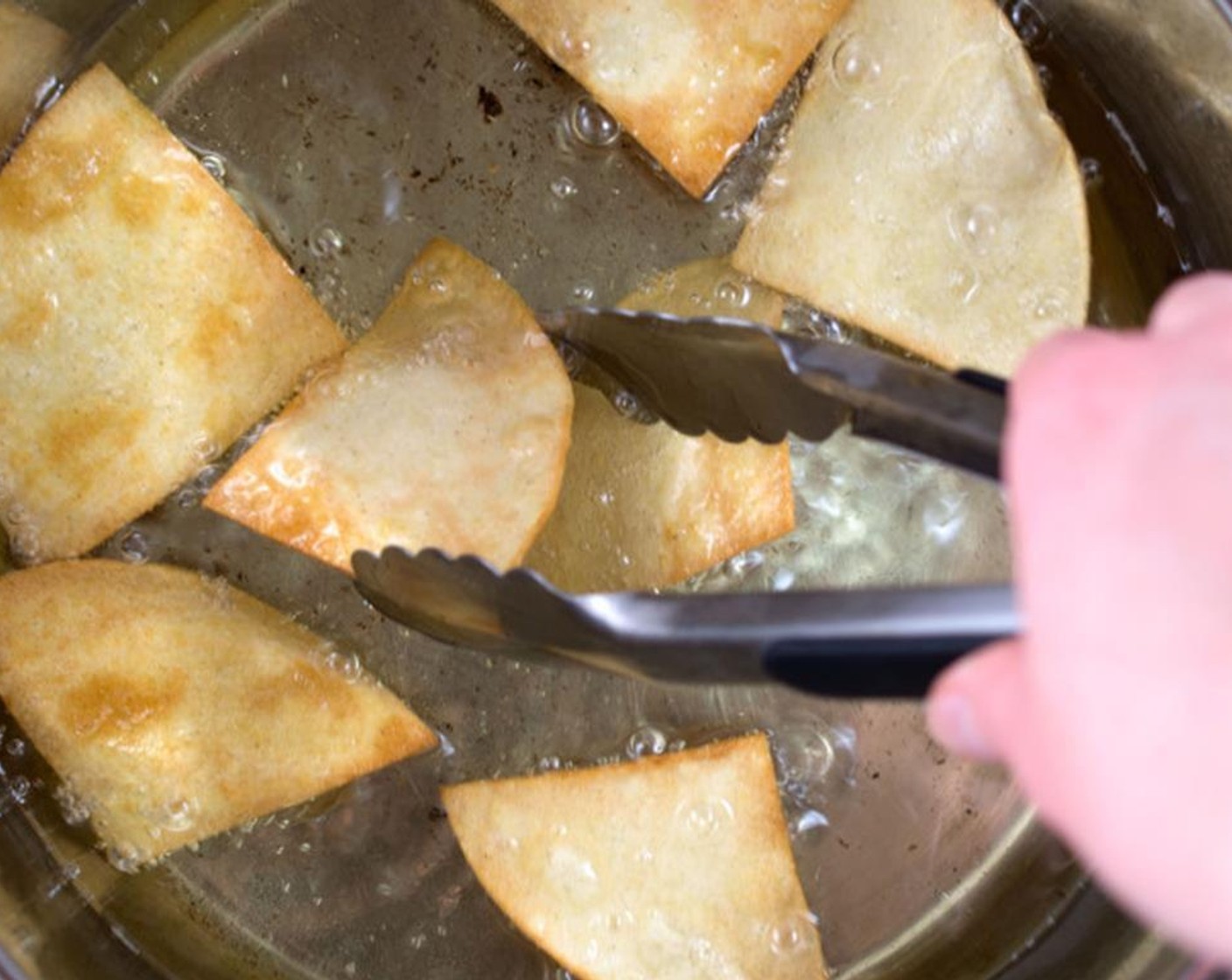 step 4 In a large saucepan on medium-high, heat Canola Oil (as needed) until it reaches 350 degrees F (180 degrees C). Add in tortilla pieces leaving enough room for them to move around and not stick to one another. Let them cook about a minute on each side.