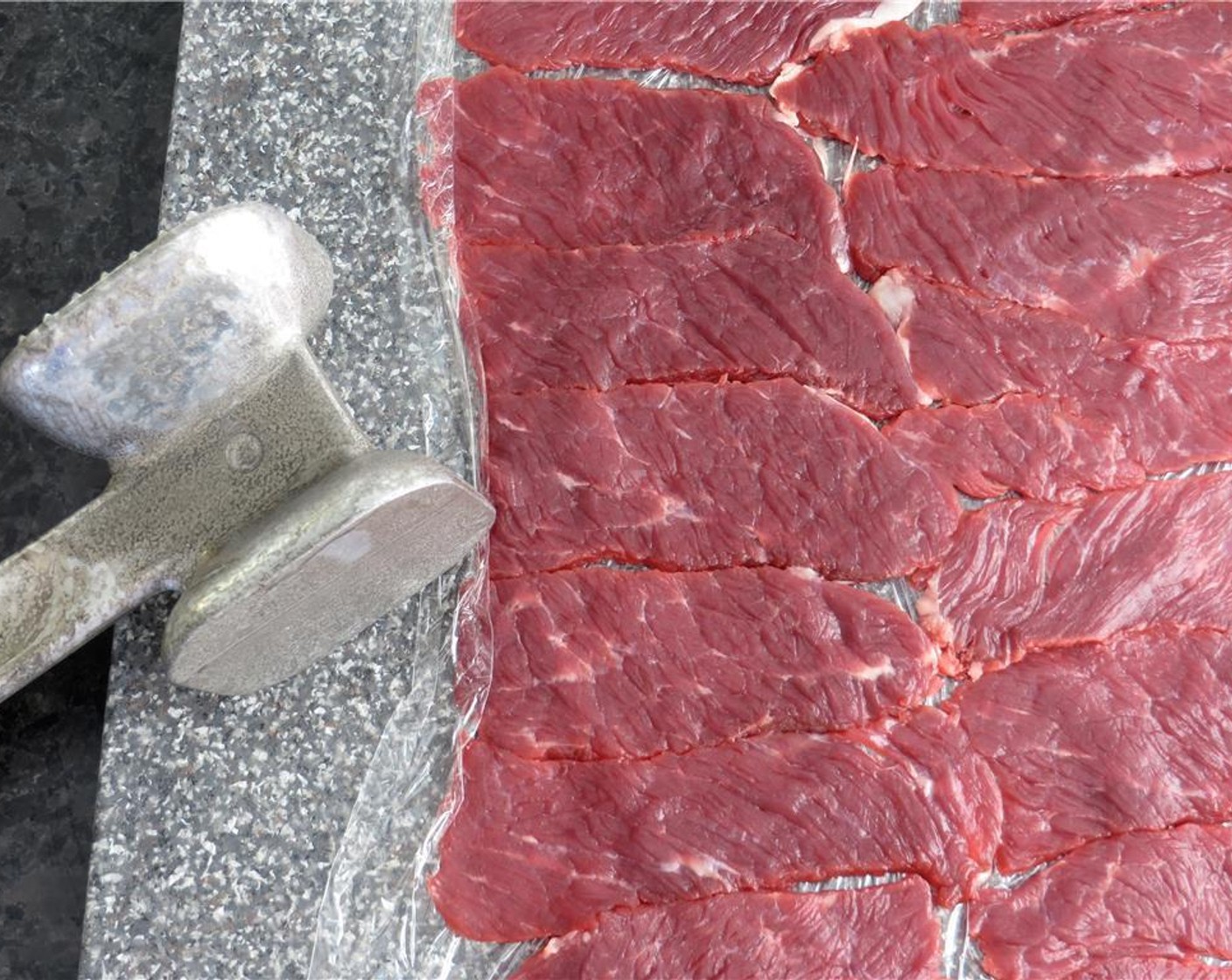 step 6 Cut another sheet of plastic wrap and lay them on top of the beef. Using the smooth side of a meat mallet, pound the beef until paper thin.