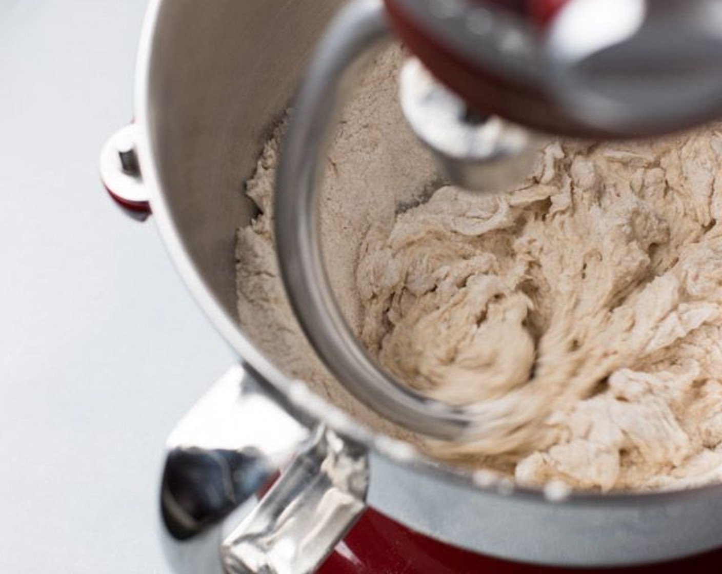 step 3 Pour water and yeast mixture into your stand mixer with a dough hook attachment. Set on low speed, gradually add the flour mixture until emptied. Mix the dough for 10 minutes in total, to allow for it to be kneaded by the dough hook. Scrape the sides of the bowl with a spatula occasionally if the flour isn't incorporating into the dough.