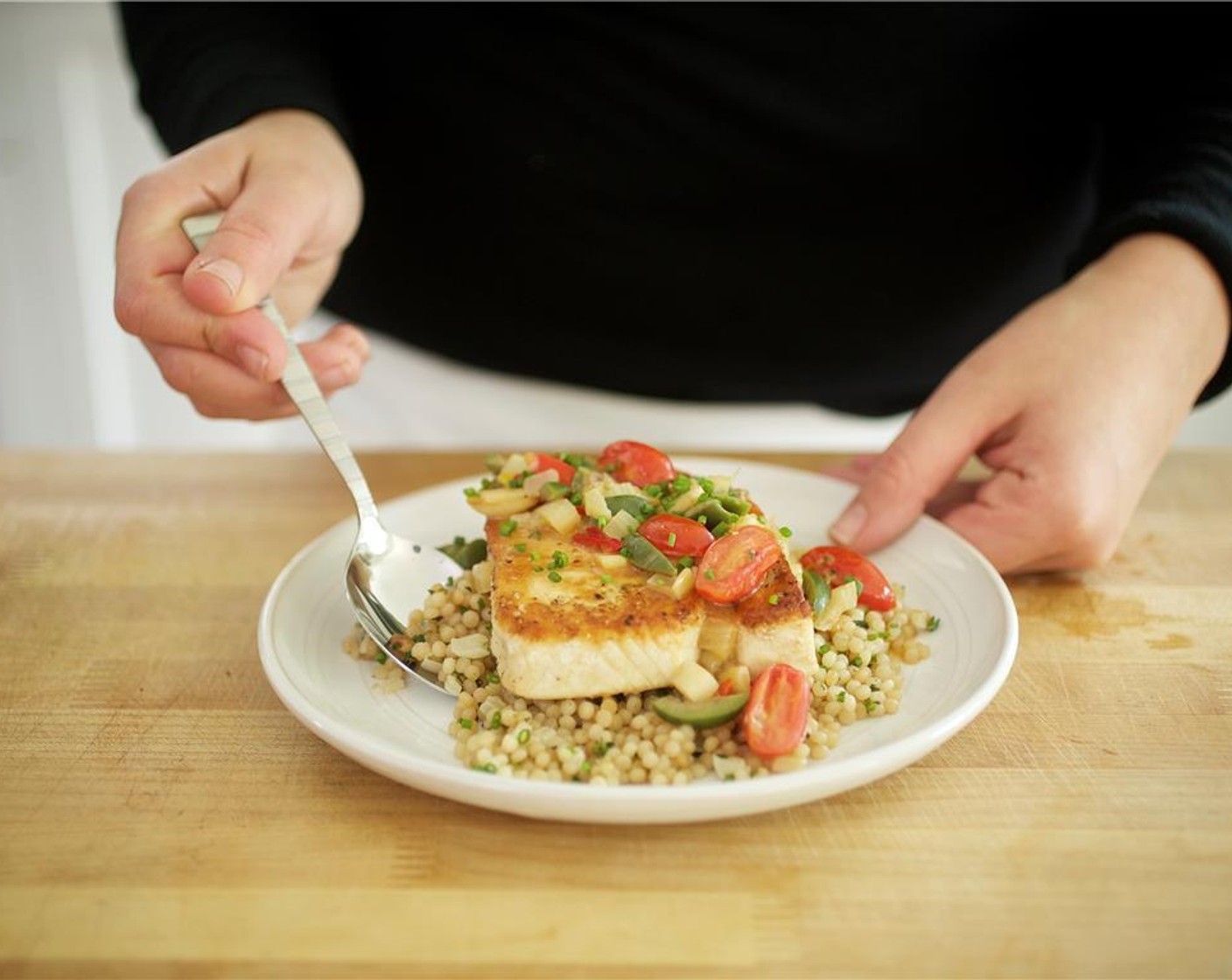 step 14 Place equal amounts of couscous in the center of two plates. Top with the swordfish filet. Drizzle remaining lemon juice on top. Spoon the tomato sauce over the fish. Garnish with remaining chives.