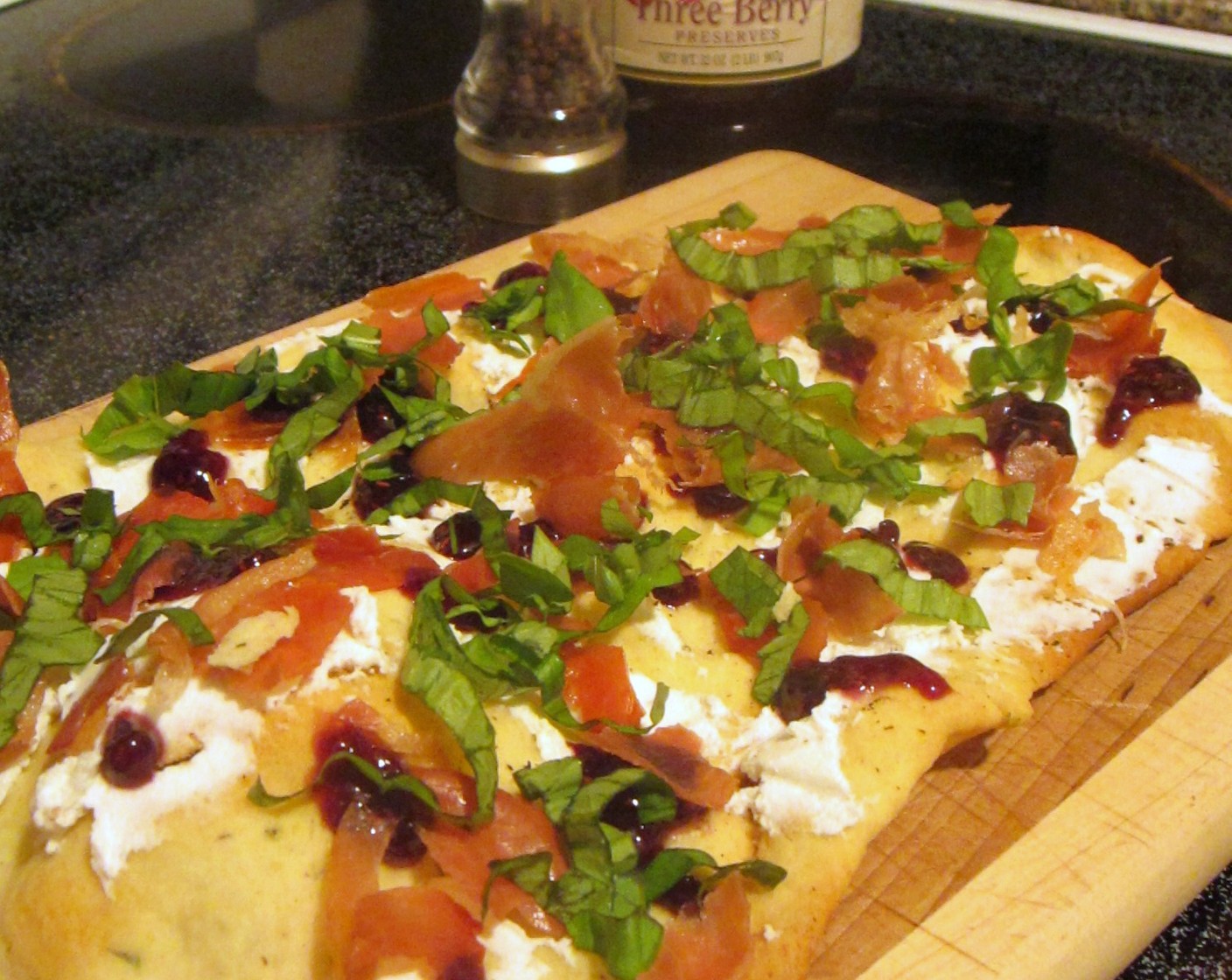 step 9 Once the flatbread is baked, spread the Goat Cheese (1/3 cup) and sprinkle crumbled prosciutto and ribbons of Fresh Basil Leaves (12) on top of the cheese. Repeat with the second flatbread. Drizzle the raspberry preserves on top of your lovely flatbreads and serve.