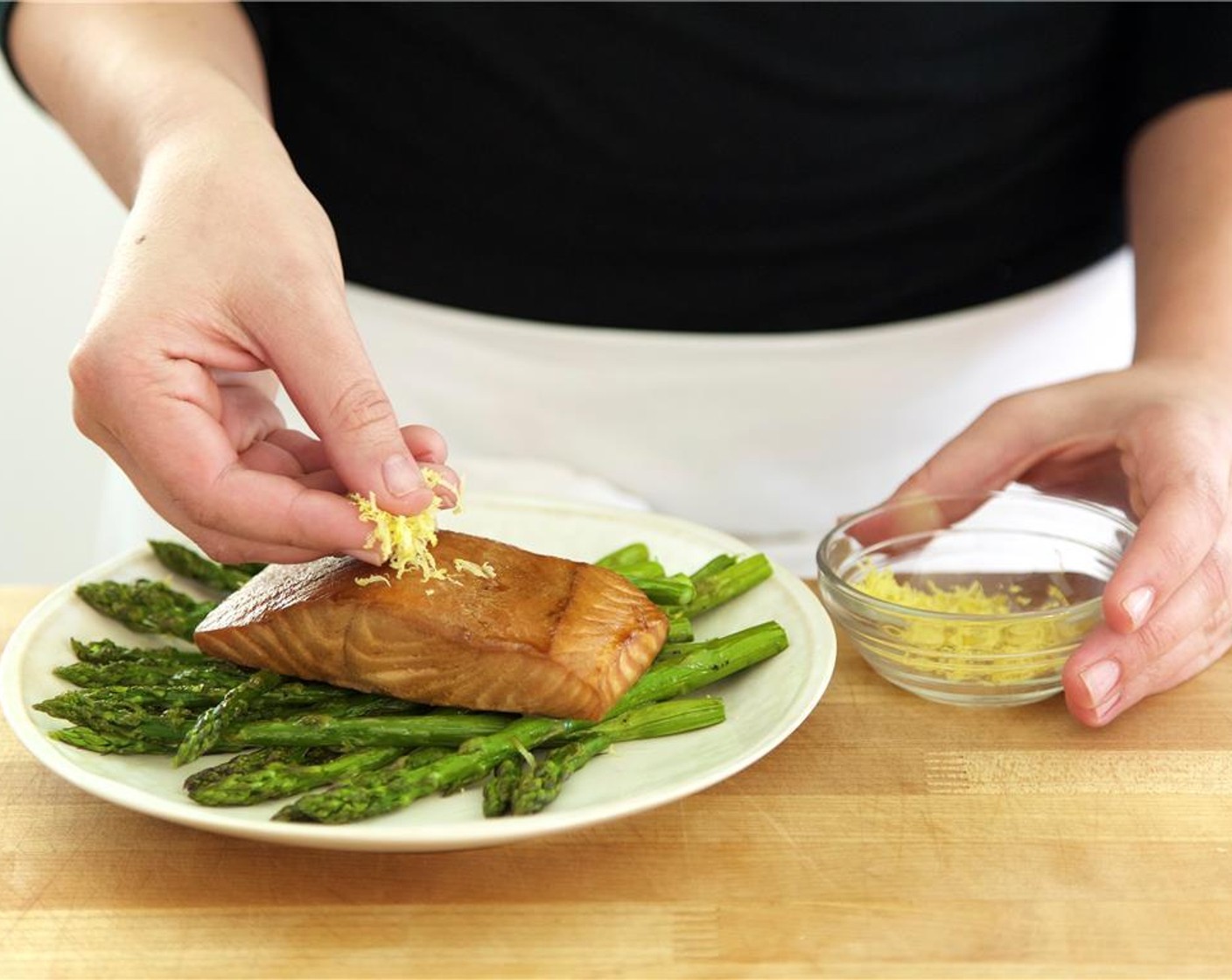 step 8 Divide the asparagus into two portions and place in the center of two plates. Stack the salmon fillets at an angle on top of the asparagus. Garnish the fish with lemon zest.