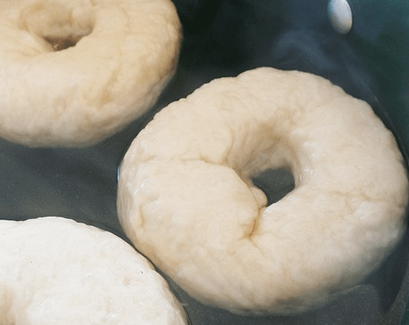 step 10 Bring a large pot of water to a boil. Reduce the heat. Use a slotted spoon or skimmer to lower the bagels into the water. Boil as many as you are comfortable with boiling. Once the bagels are in, it shouldn’t take too long for them to float to the top (a couple seconds). Let them sit there for 1 minute, and them flip them over to boil for another minute.