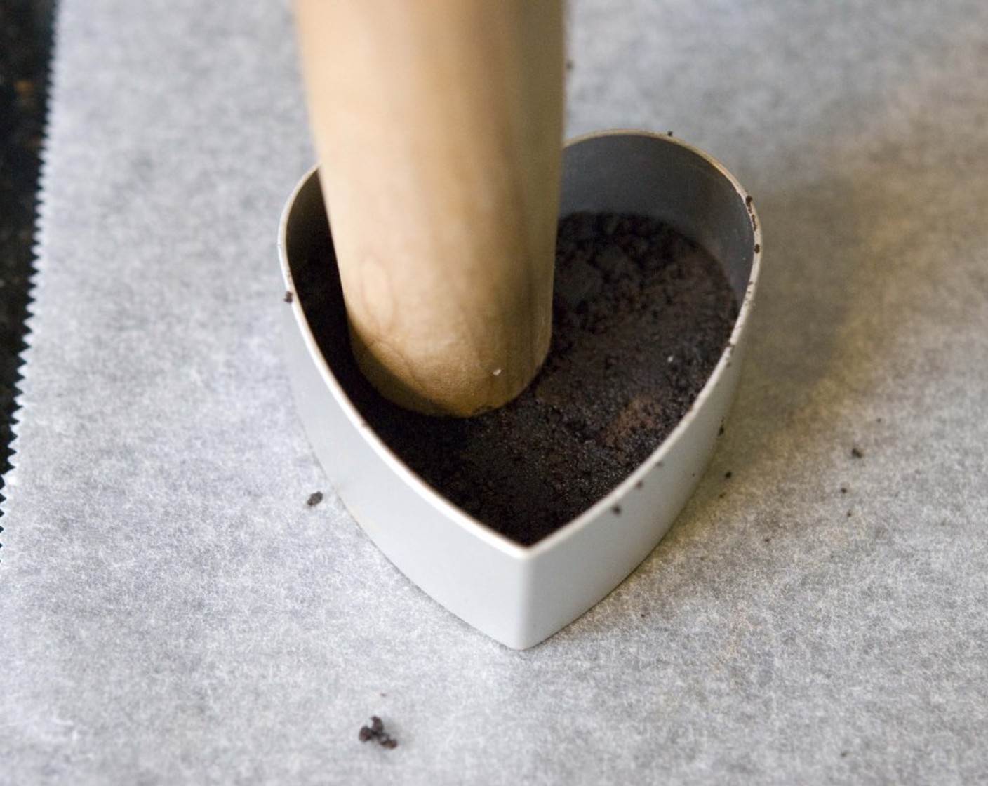 step 6 Grab a baking paper and a heart-shaped cookie cutter. Place some crushed cookie inside the cookie cutter and using the edge of your rolling pin firmly press the crumble inside the cutter.