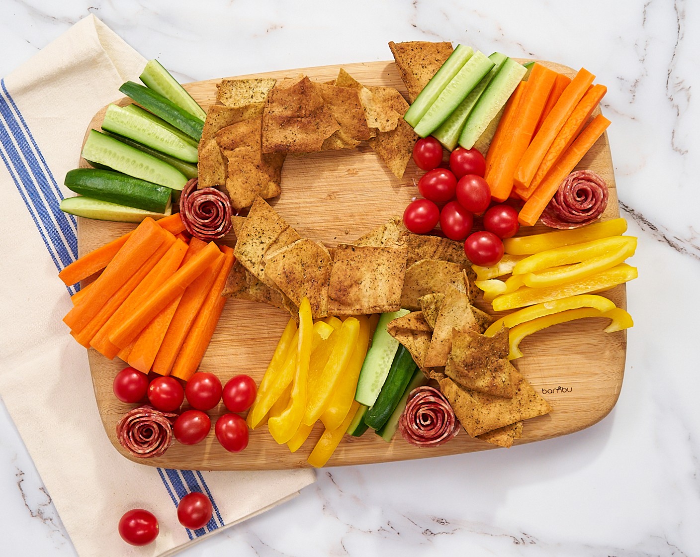 step 9 Place the roses, Cucumbers (2), Bell Pepper (1), and Carrots (2) around the board. Scatter the Cherry Tomatoes (2 cups) in two places, and make a “swirl” of Pita Chips (to taste) through the center. Leave space for the dips.