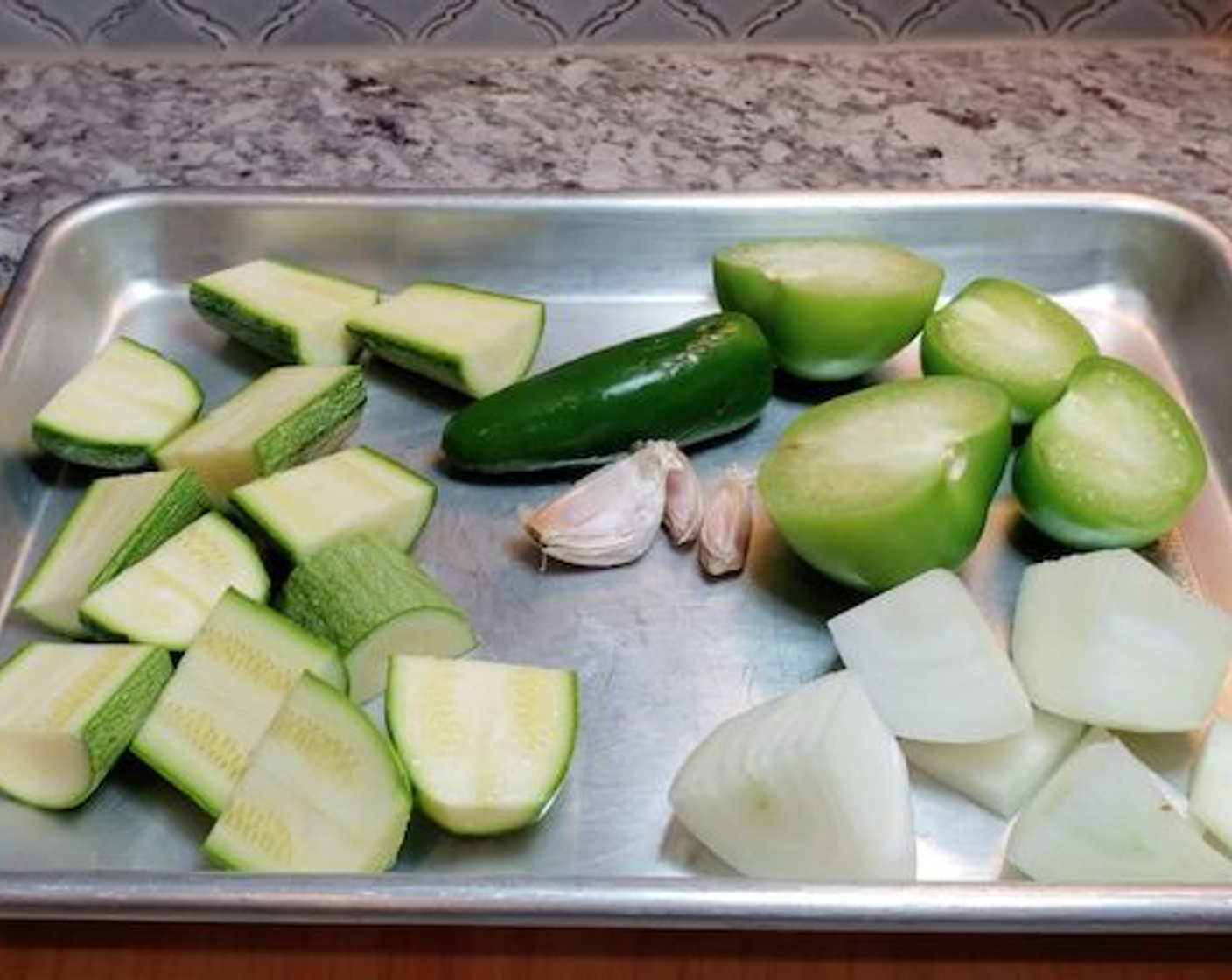 step 3 Halve tomatillos. Chop Onion (1/2) and Zucchini (1) into large chunks. Be sure to leave the skin on the garlic.