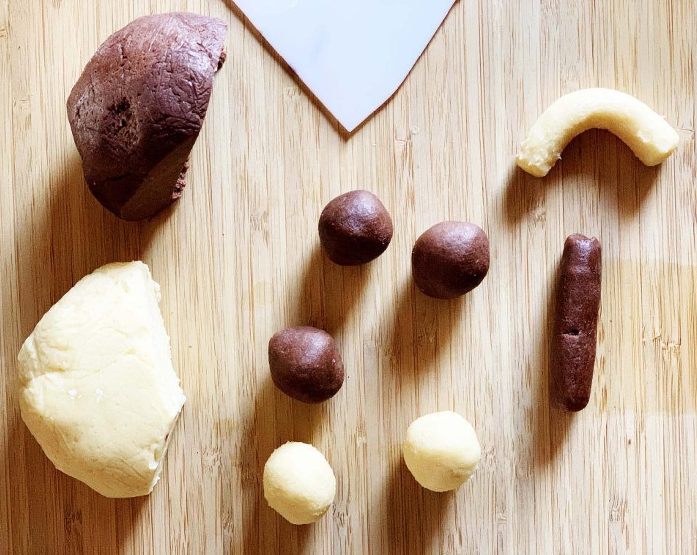 step 8 To shape your cookies, divide each mixture into a small ball, 12 grams each. Then roll each ball into a 1/2-inch (1cm) thick and 6 centimeters long roll. Curve each into a half-moon and bring the chocolate and cream sides together to make a circle.