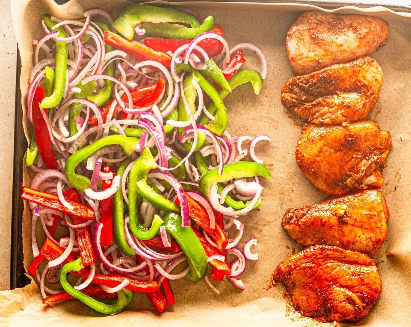 step 3 While the chicken is marinating, slice Red Onion (1) and Bell Peppers (2). Add them to a sheet pan and season with Olive Oil (1/2 Tbsp), Salt, and Ground Black Pepper (1/4 tsp) to taste. Place the chicken on the sheet pan with the vegetables.