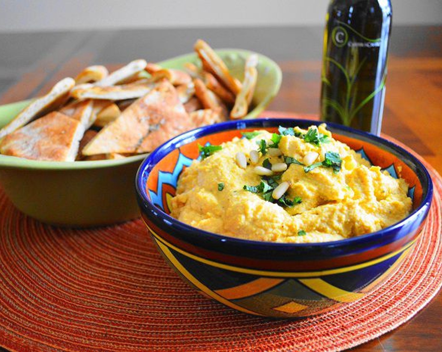 step 7 Transfer it to a pretty bowl and drizzle it with more Olive Oil (as needed). Garnish it with the Fresh Cilantro (1 Tbsp) and Pine Nuts (as needed) and serve it with the pita chips. Enjoy!