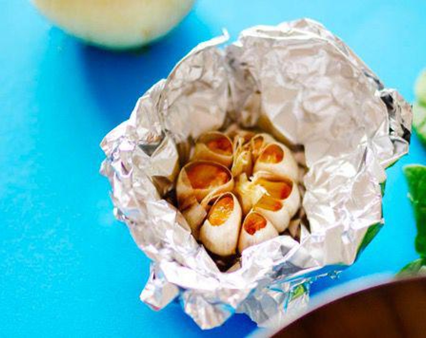 step 1 Chop the top portion off the Garlic (1 bulb) to expose a bit of the cloves, leaving the paper intact. Set bulb on a sheet of aluminum foil and drizzle Olive Oil (1 Tbsp) onto it, letting the oil sink into the cloves. Wrap the bulb up in foil and bake for 30 minutes at 400 degrees F (200 degrees C), or until cloves are soft and lightly browned.