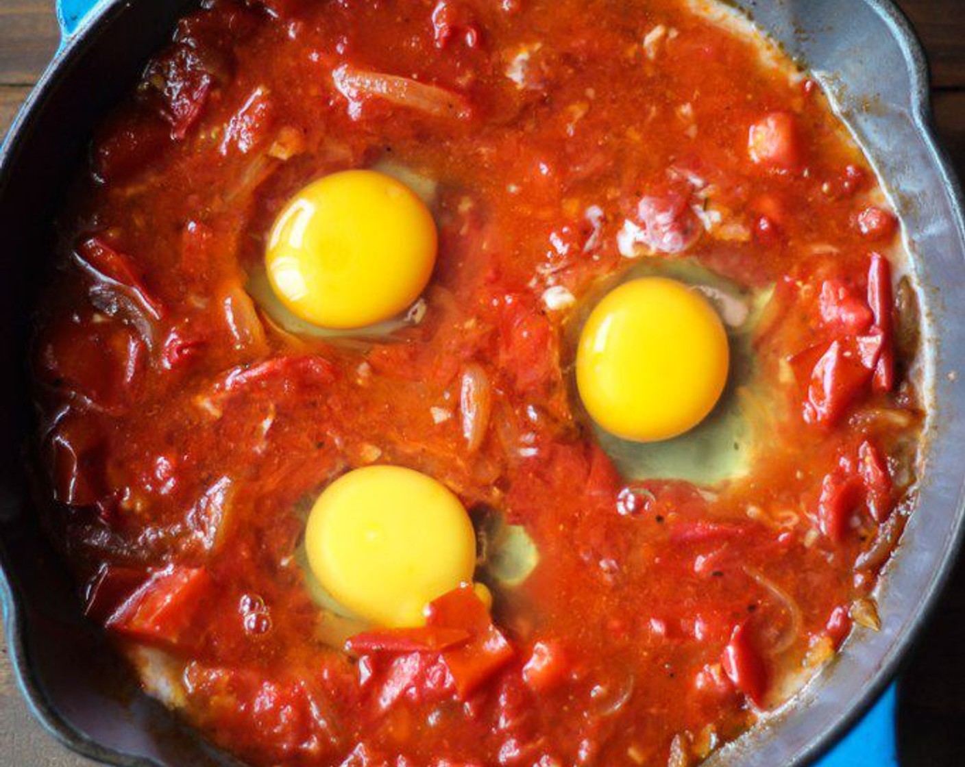 step 6 Make three wells in the tomato sauce, for the Eggs (3) and crack one egg into each well.