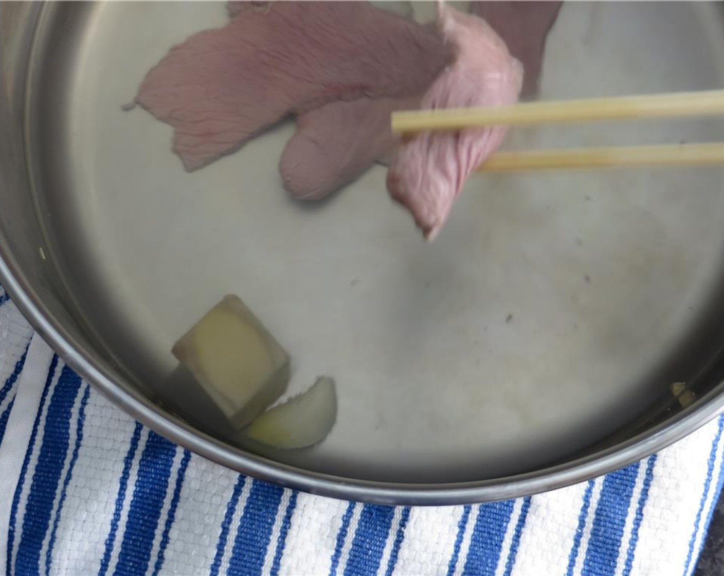 step 7 Remove the vinaigrette from the refrigerator and set close by the simmering water. Using tongs, gently drop a few slices of beef into the water for up to 10 seconds (less if you like your beef rare).