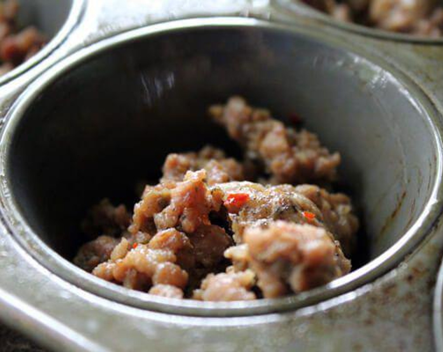 step 3 In each muffin tin, spoon Pork Sausages (1 1/2 cups) into the bottom.