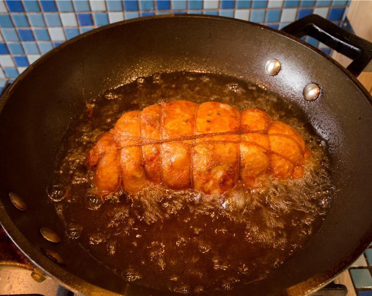 step 12 Adjust flame to maintain a 350 degrees F (180 degrees C) temperature. Using a large metal ladle, spoon hot oil over the exposed portions of the roast continuously until the bottom half is cooked and crisp, about 5 minutes.