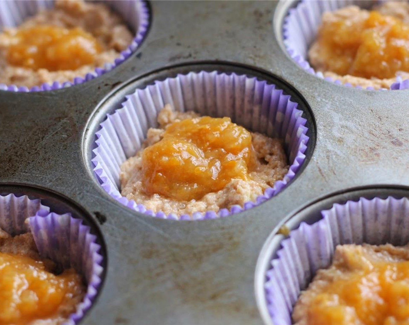 step 5 Fill prepared muffin tins half way with batter. Hollow out a little hole in the batter in each muffin cup. Put a teaspoon of Peach Preserves (1/3 cup) into each muffin cup. Spoon batter over the top of each, filling almost to the top.